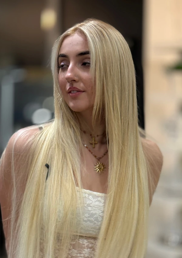 Long, straight platinum-blonde hair with a pale knit top