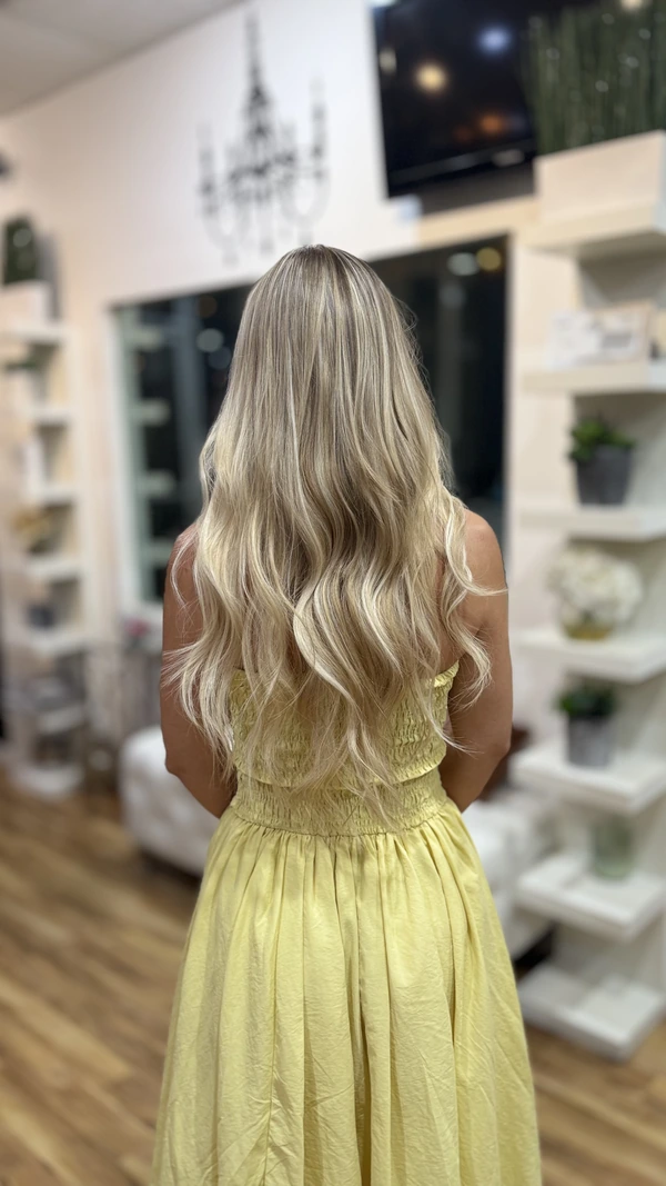 Long, loose light-blonde waves over a darker root, seen from behind